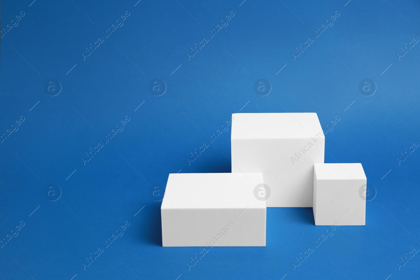 Photo of Product photography props. Podiums of different geometric shapes on blue background, space for text