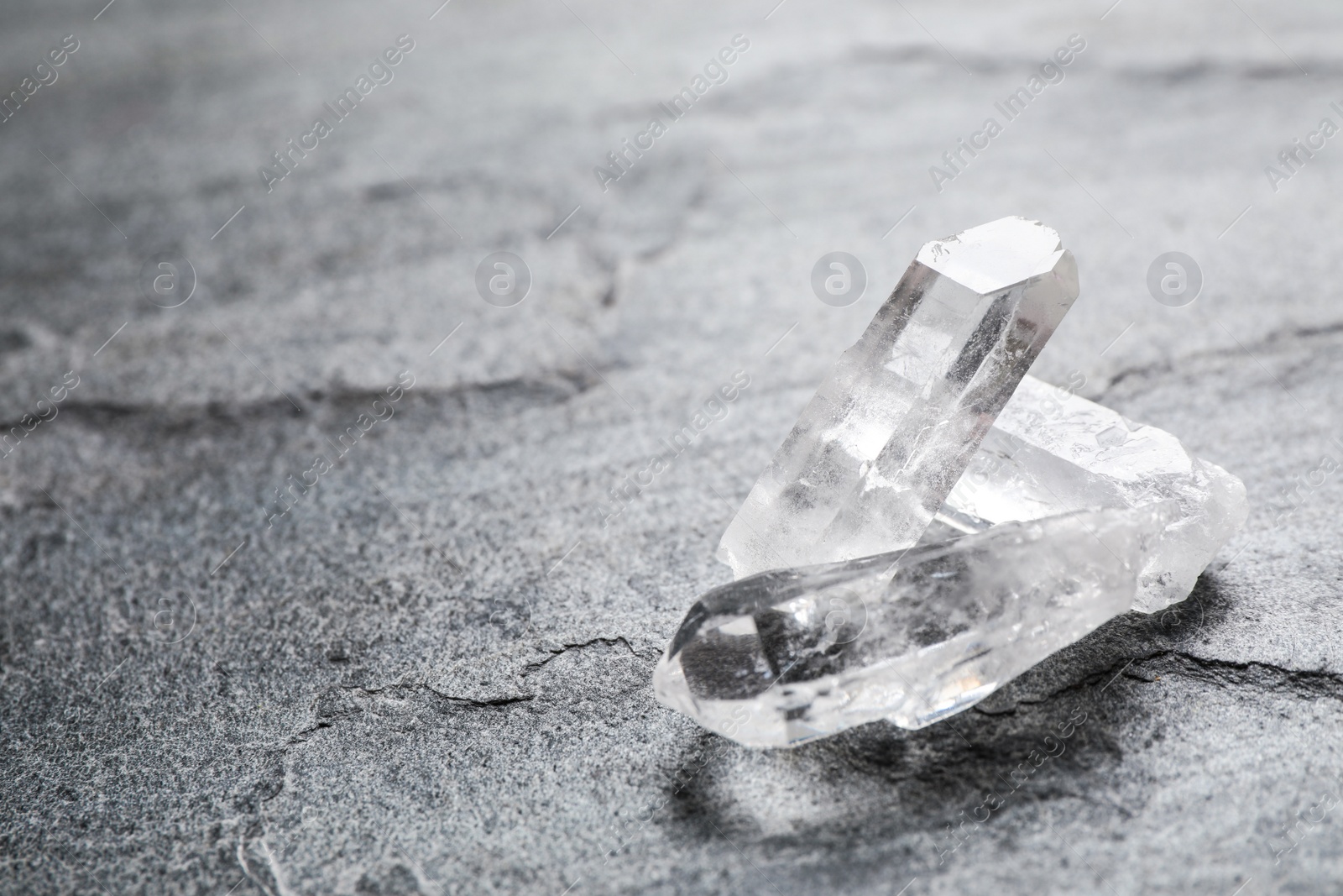 Photo of Beautiful rock crystal gemstones on grey table, space for text