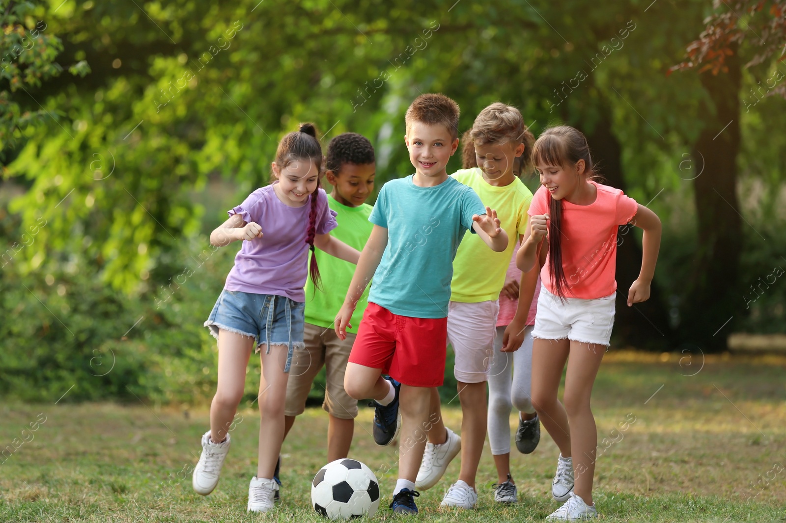 Photo of Cute little children playing with soccer ball in park