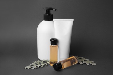 Photo of Cosmetic products and silver leaves on dark grey background