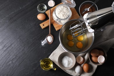 Photo of Making dough. Raw eggs in bowl of stand mixer and ingredients on black table, flat lay