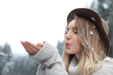 Photo of Young woman playing with snow outdoors. Winter vacation