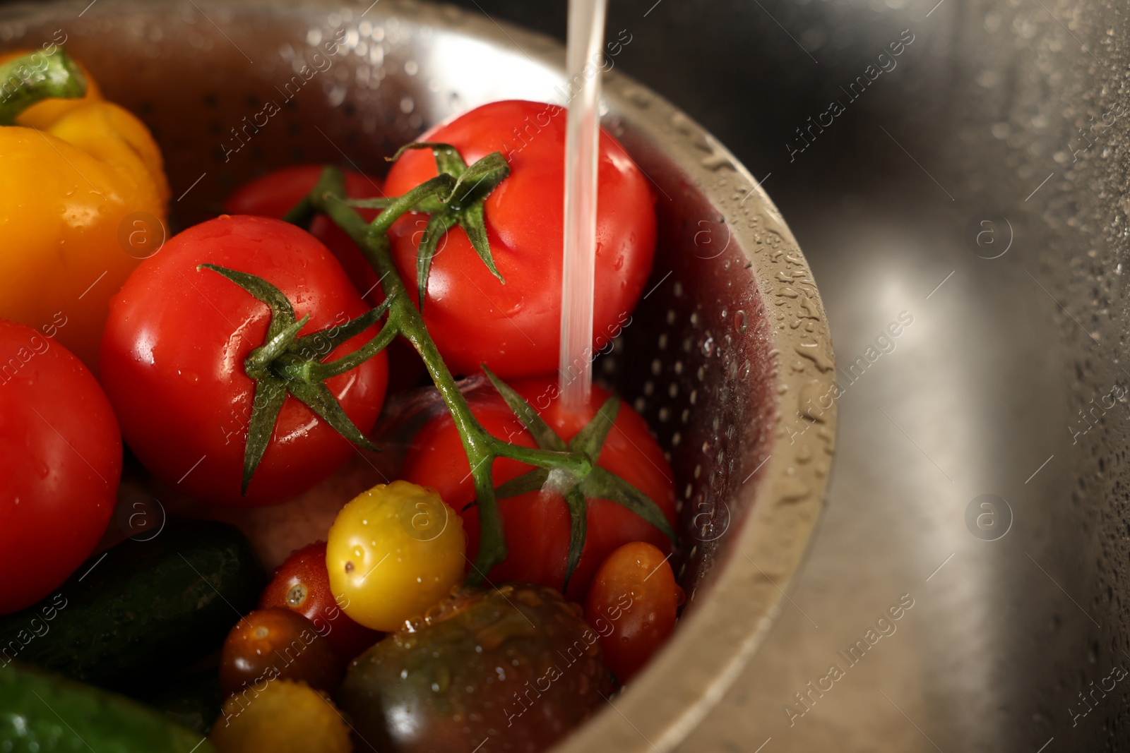 Photo of Washing different vegetables with tap water in metal colander inside sink, closeup