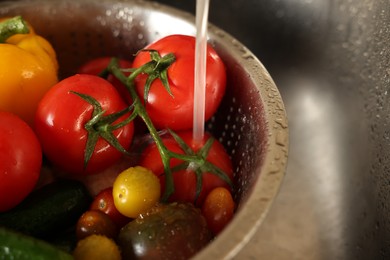 Photo of Washing different vegetables with tap water in metal colander inside sink, closeup