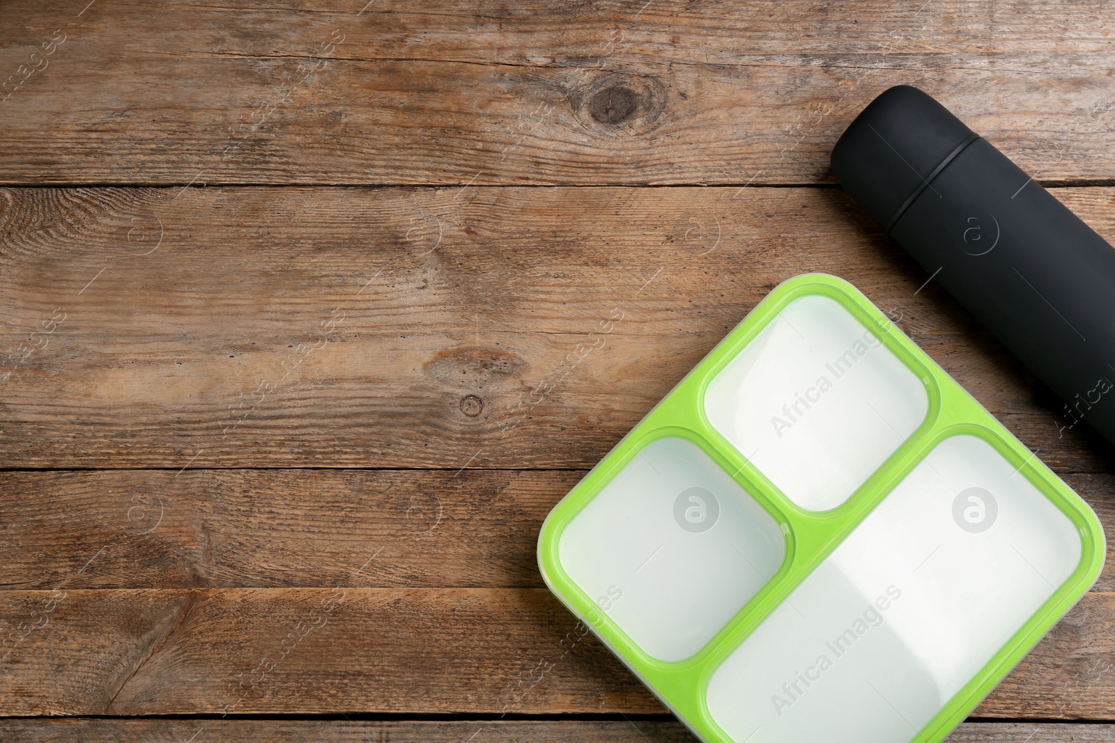 Photo of Thermos and lunch box on wooden table, flat lay. Space for text