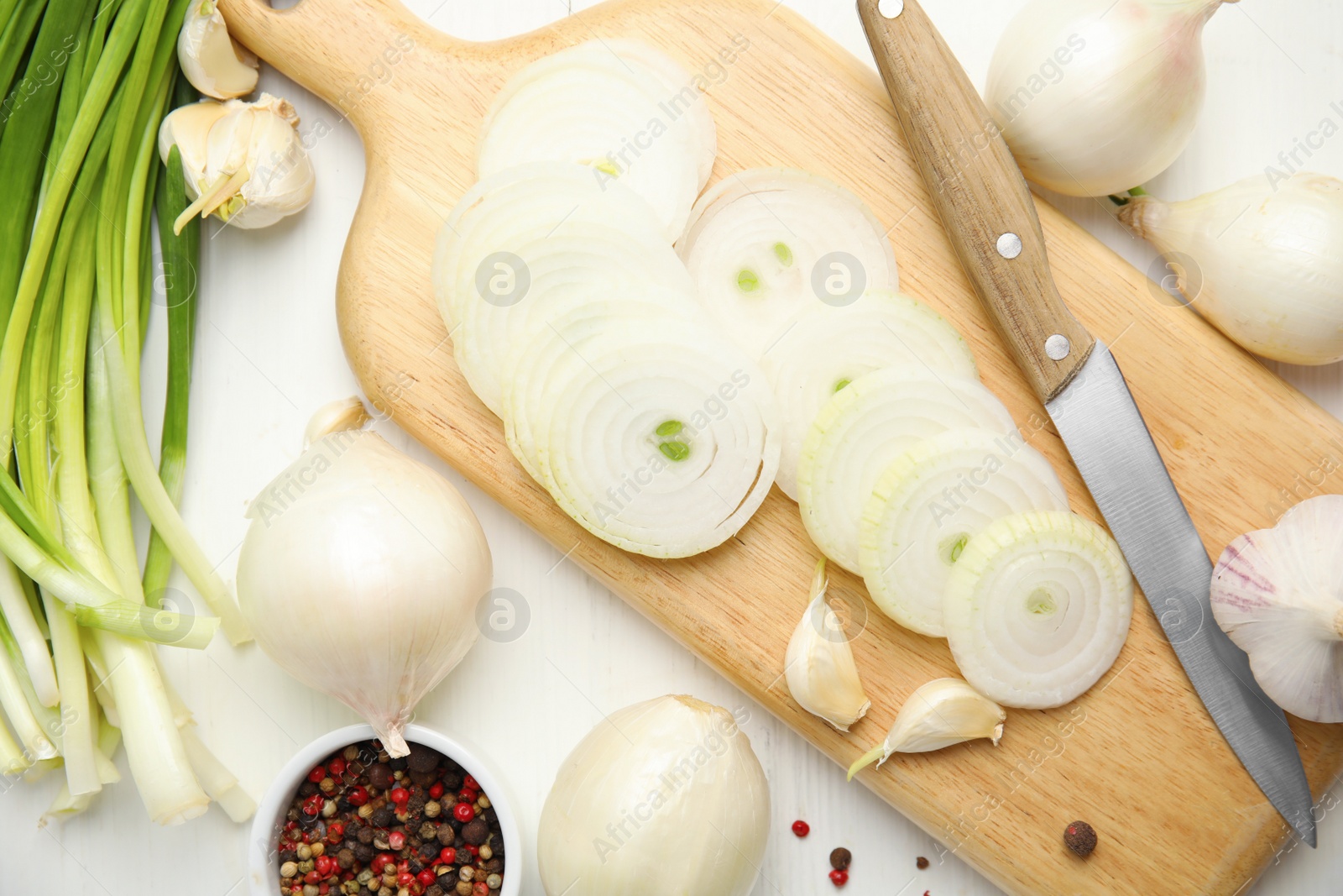 Photo of Garlic, cut onion and bowl with peppers mix on white wooden table, flat lay