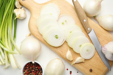 Garlic, cut onion and bowl with peppers mix on white wooden table, flat lay