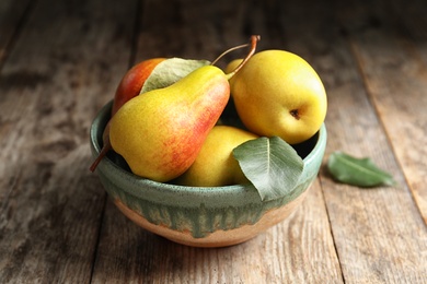 Photo of Bowl with ripe pears on wooden table