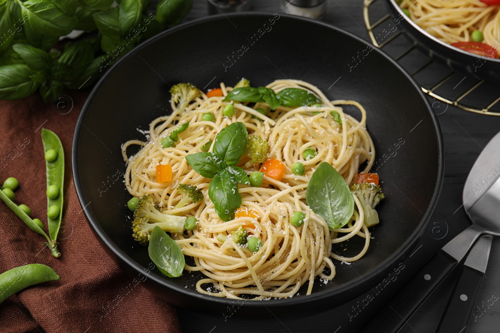 Photo of Delicious pasta primavera with basil, broccoli and peas served on table, closeup