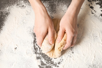 Young woman kneading dough for pasta on table, top view