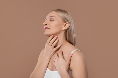 Photo of Beautiful woman touching her neck on beige background
