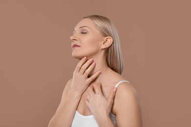 Beautiful woman touching her neck on beige background