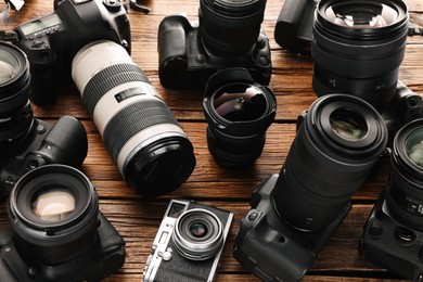 Photo of Modern cameras on wooden table, closeup. Professional photography equipment