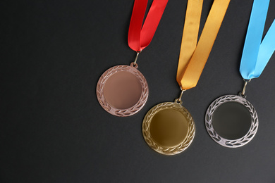 Gold, silver and bronze medals on black background, flat lay. Space for design