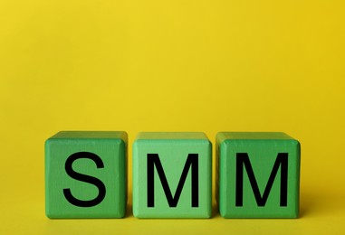 Photo of Green cubes with abbreviation SMM (Social media marketing) on yellow background