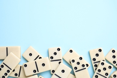 Classic domino tiles on light blue background, flat lay. Space for text