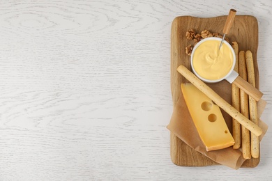 Pot of tasty cheese fondue and products on wooden table, top view. Space for text