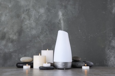 Photo of Composition with aroma humidifier on table against grey background. Space for text