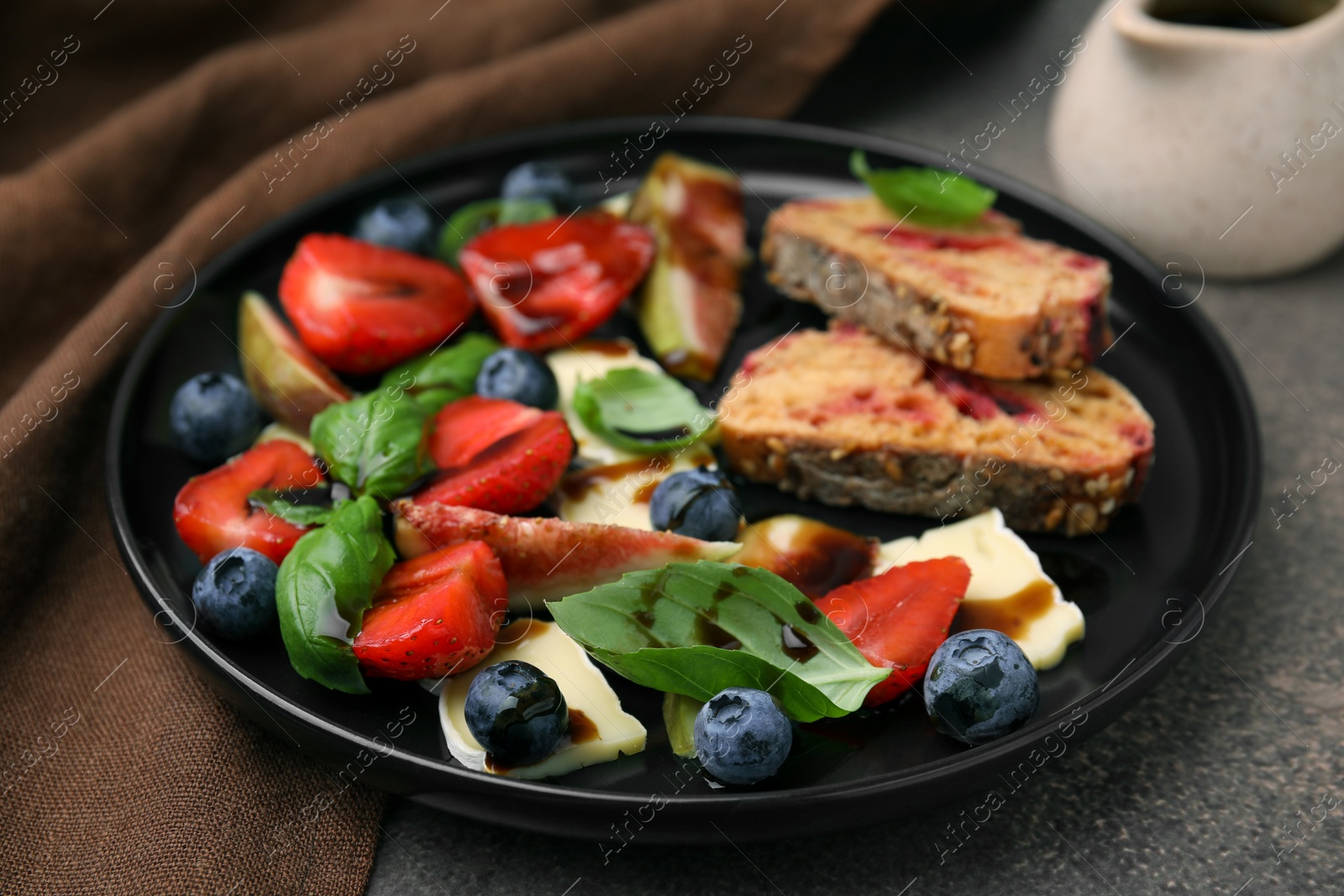 Photo of Delicious salad with brie cheese, berries and balsamic vinegar on brown table, closeup