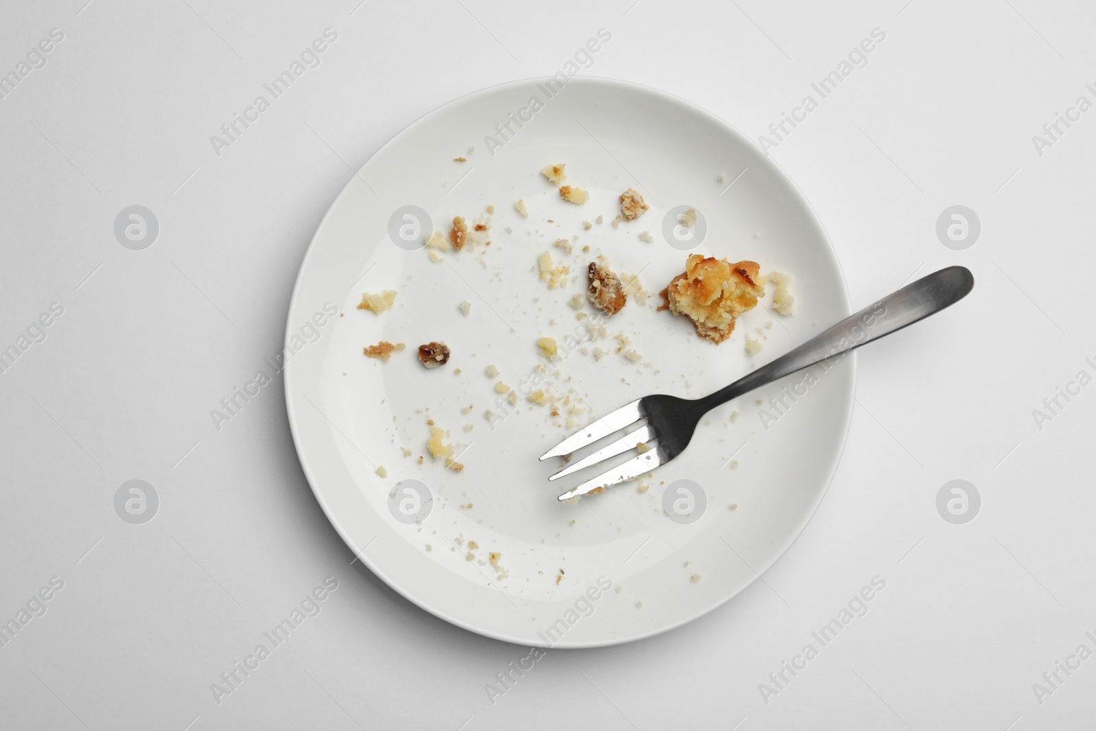 Photo of Dirty plate with food leftovers and fork on white background, top view