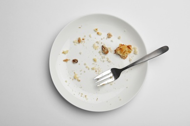 Photo of Dirty plate with food leftovers and fork on white background, top view