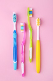 Many different toothbrushes on pink background, flat lay