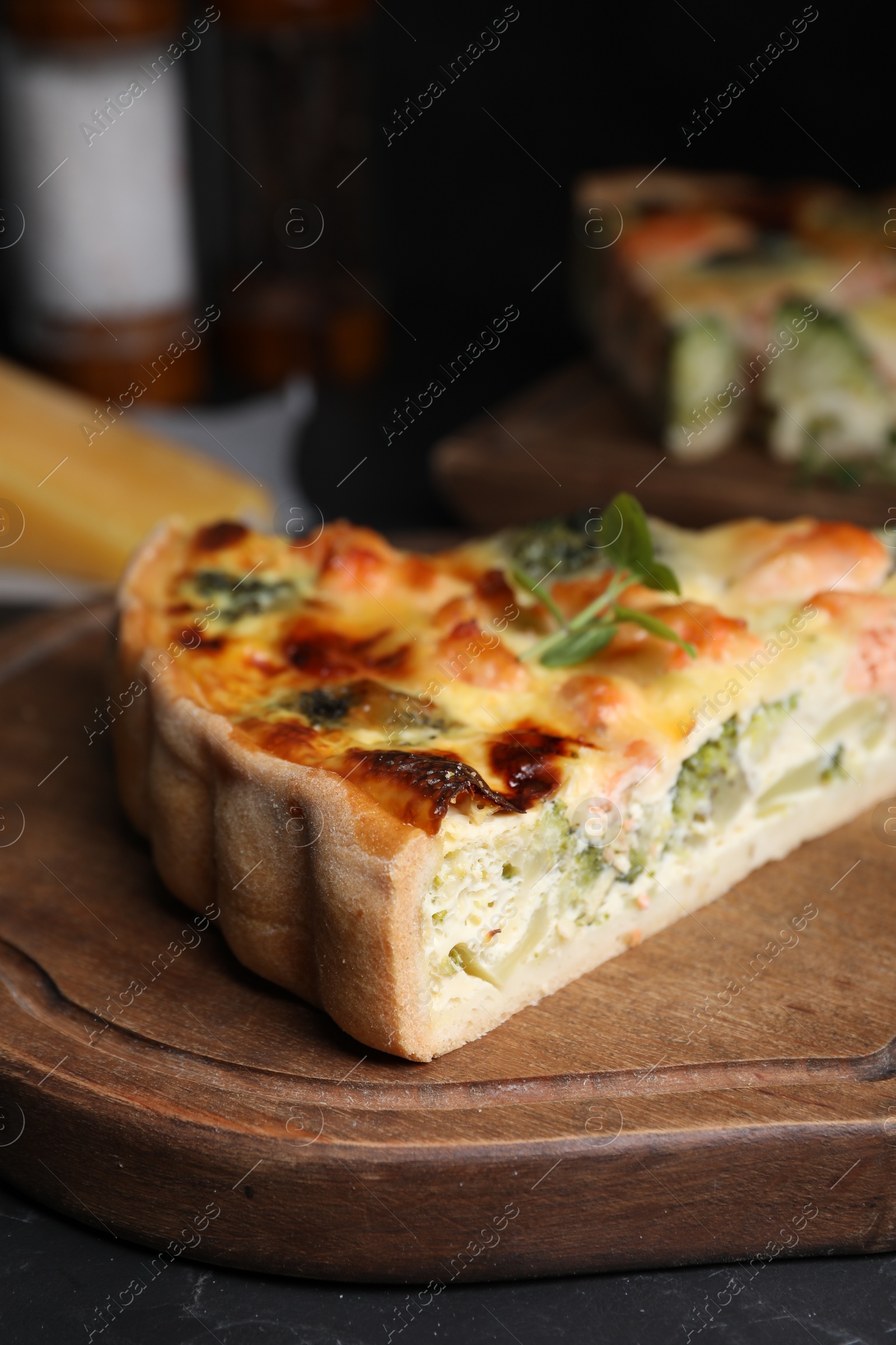 Photo of Piece of delicious homemade quiche with salmon and broccoli on wooden board, closeup