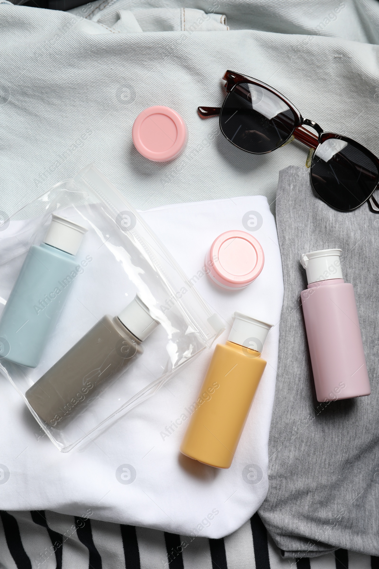 Photo of Cosmetic travel kit, plastic bag and accessories in suitcase, top view