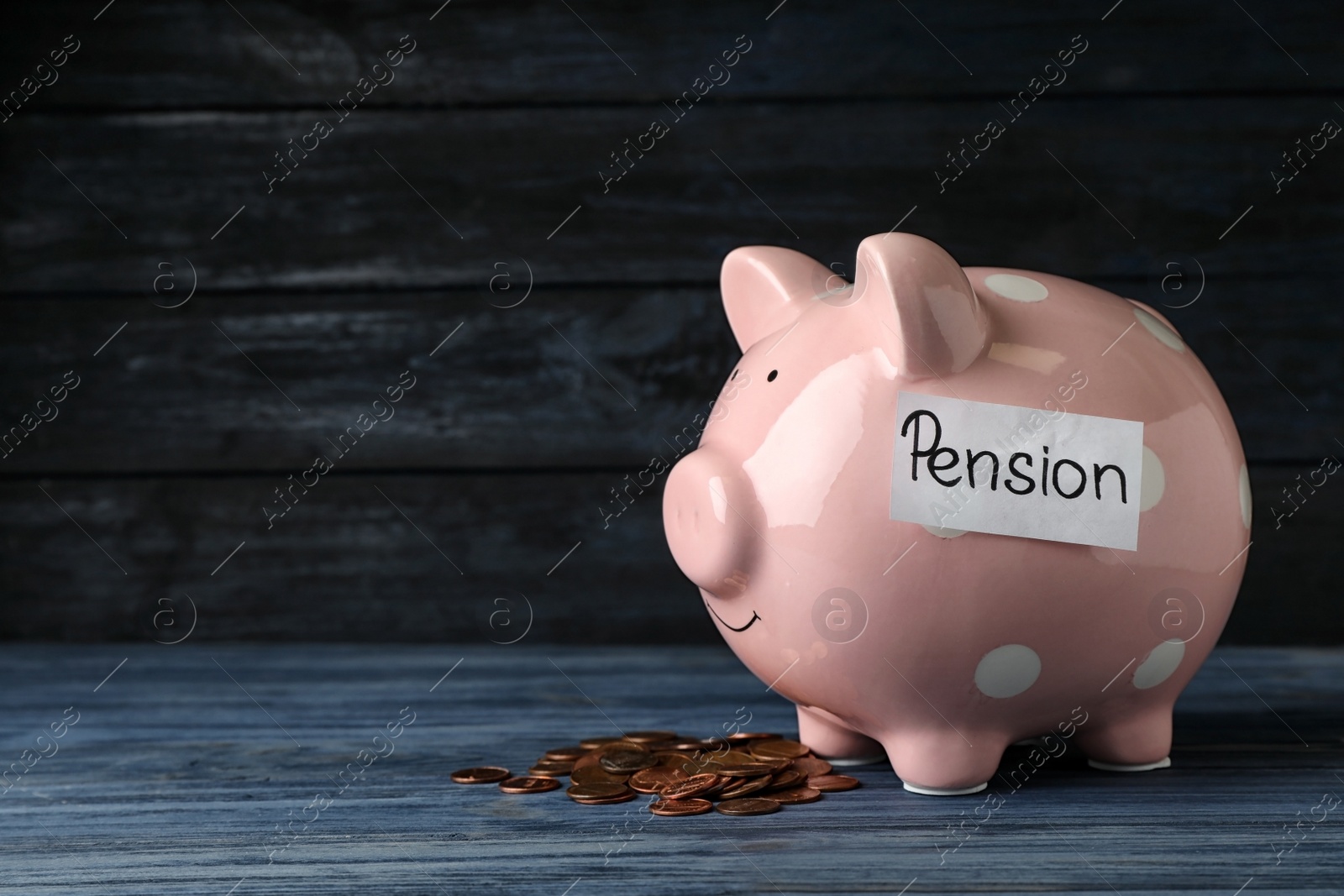 Photo of Piggy bank with word PENSION and coins on table. Space for text