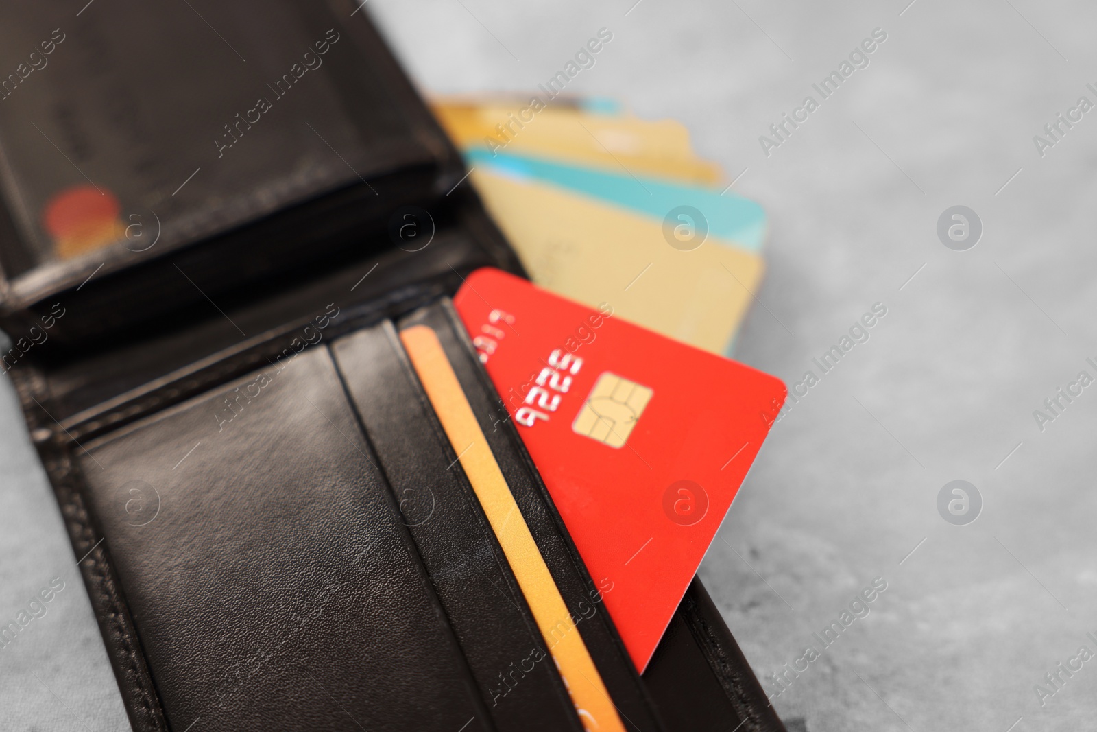 Photo of Many different credit cards and leather wallet on grey table, closeup