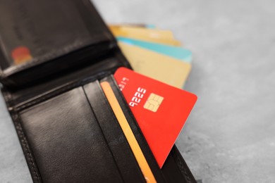 Photo of Many different credit cards and leather wallet on grey table, closeup