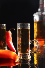 Photo of Red hot chili peppers and vodka on black table