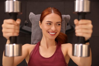 Photo of Athletic young woman doing exercise with dumbbells in gym, top view