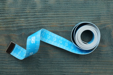 Measuring tape on light blue wooden table, top view