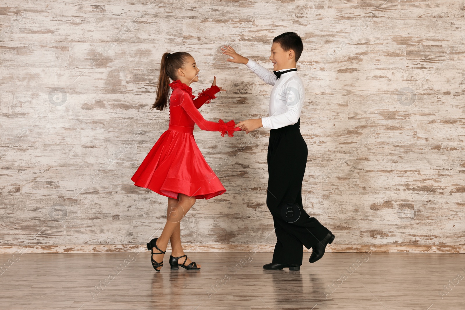 Photo of Beautifully dressed couple of kids dancing together in studio