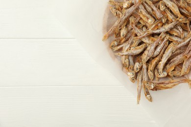 Photo of Tasty dried anchovies on white wooden table, top view. Space for text