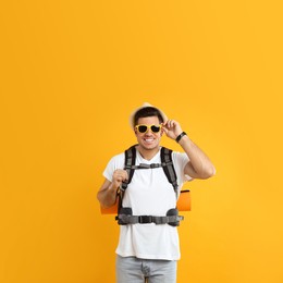 Photo of Male tourist with travel backpack on yellow background