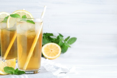 Photo of Delicious iced tea with lemon and mint on white wooden table. Space for text
