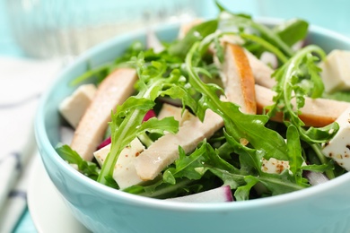 Photo of Delicious salad with chicken, arugula and feta cheese in bowl, closeup