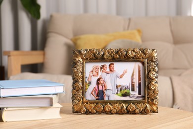 Frame with family photo and books on wooden table indoors