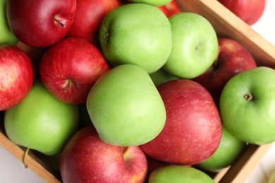Photo of Wooden crate with ripe red and green apples on white table, top view