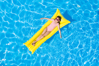 Image of Cute little girl with inflatable mattress in swimming pool, top view. Summer vacation