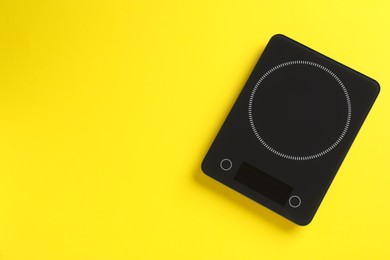 Modern digital kitchen scale on yellow background, top view. Space for text