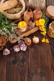 Photo of Jar, bottles of essential oils and different herbs on wooden table, above view. Space for text