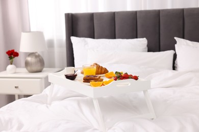 Photo of Tray with delicious breakfast on bed in room