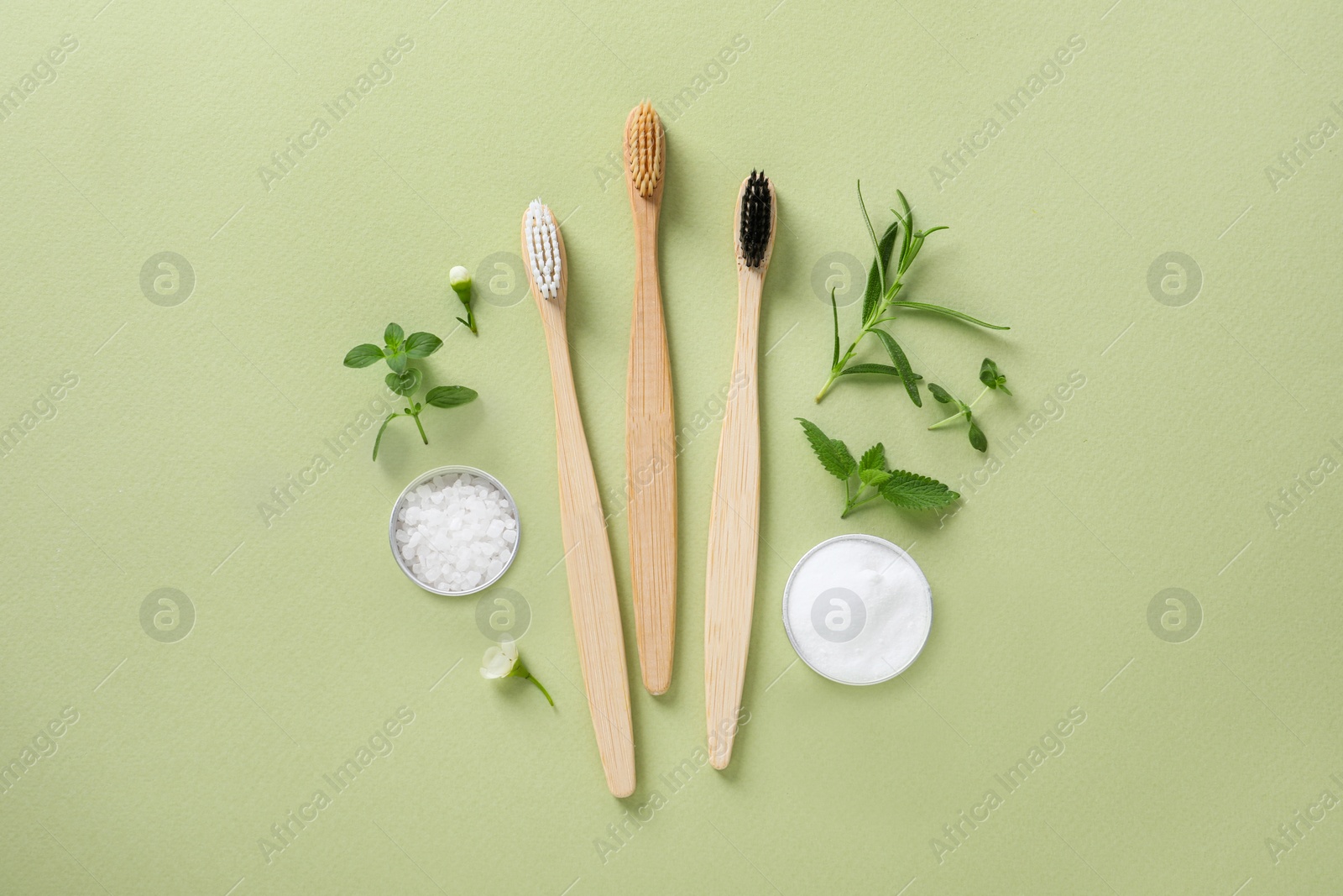 Photo of Flat lay composition with toothbrushes and herbs on light olive background