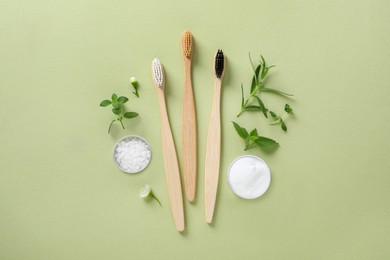 Flat lay composition with toothbrushes and herbs on light olive background