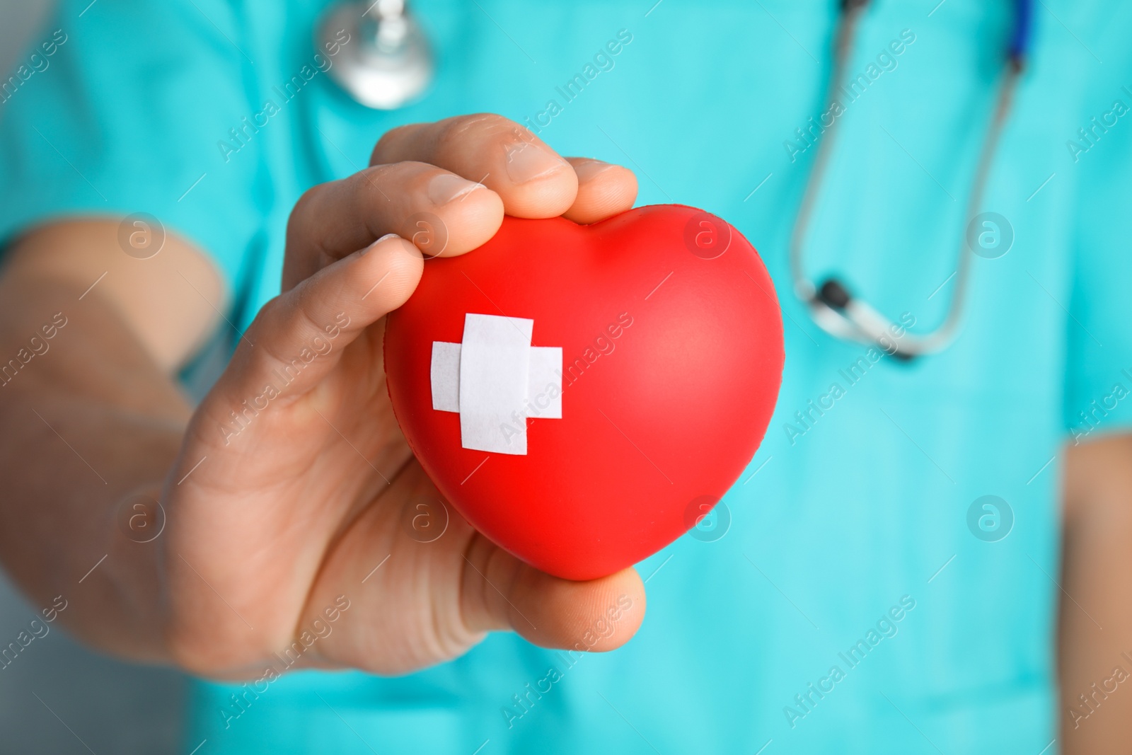 Photo of Doctor holding red heart with adhesive plasters, closeup. Cardiology concept