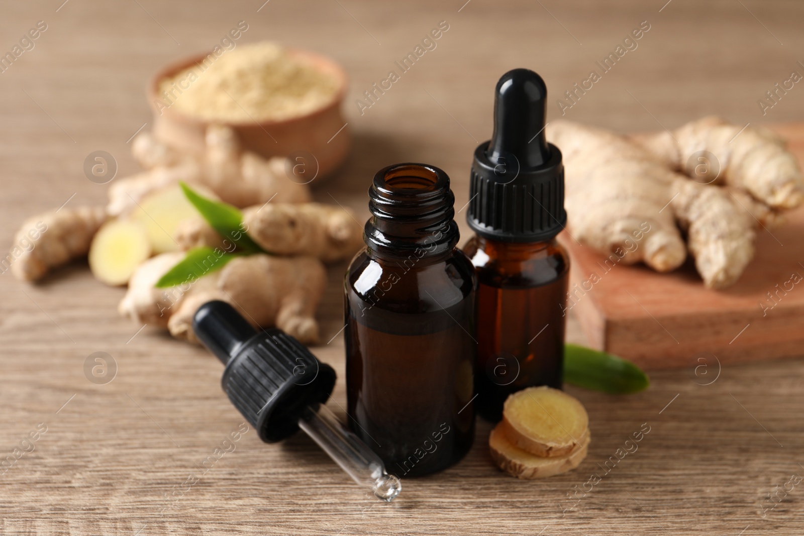 Photo of Ginger essential oil in bottles on wooden table