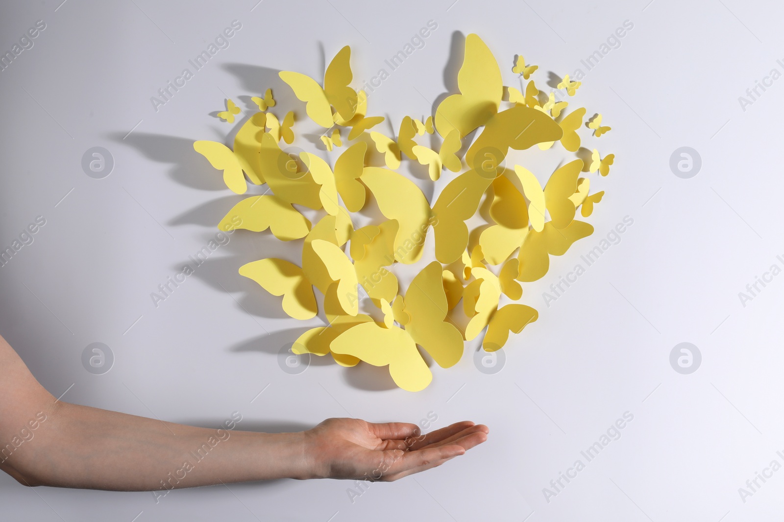 Photo of Woman with yellow paper butterflies on white background, top view